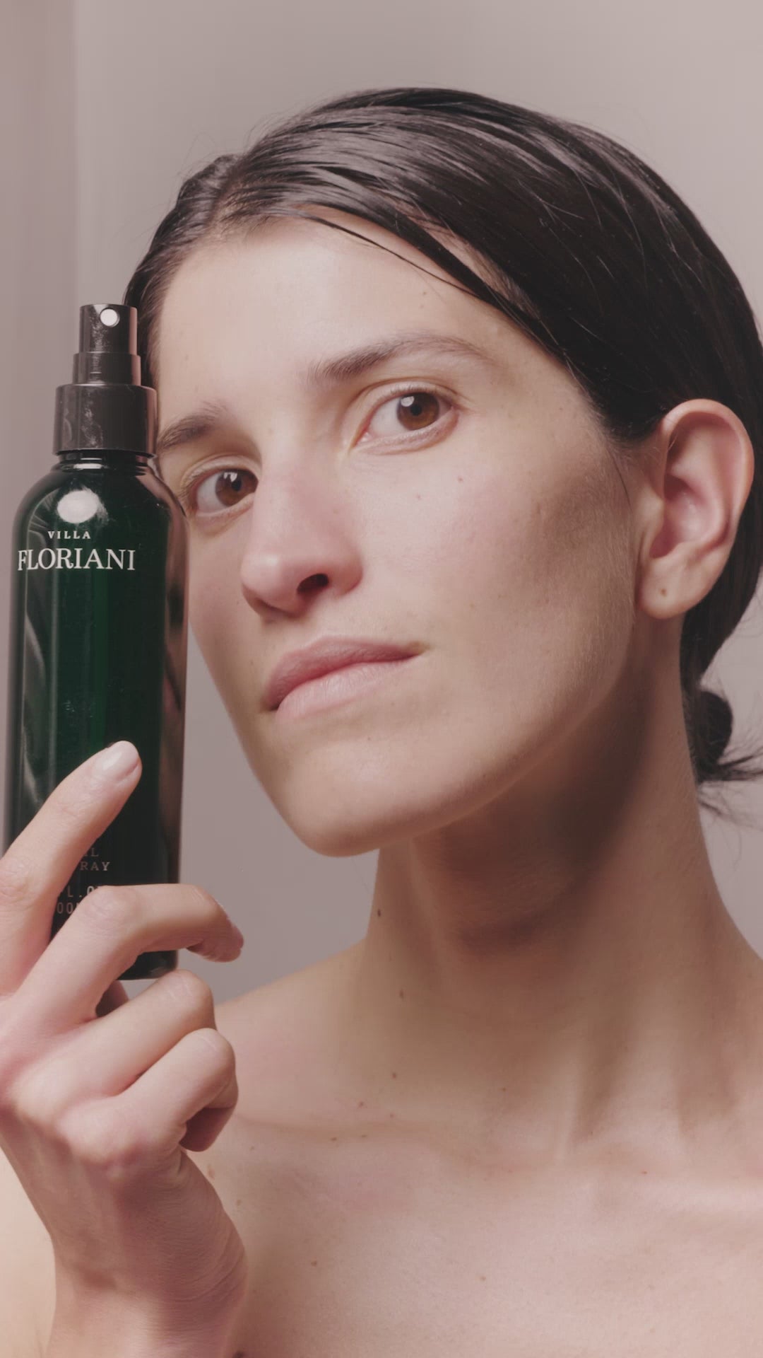 Model holding Villa Floriani Olive Oil Spray bottle a natural nourishing body oil for radiant and healthy skin.